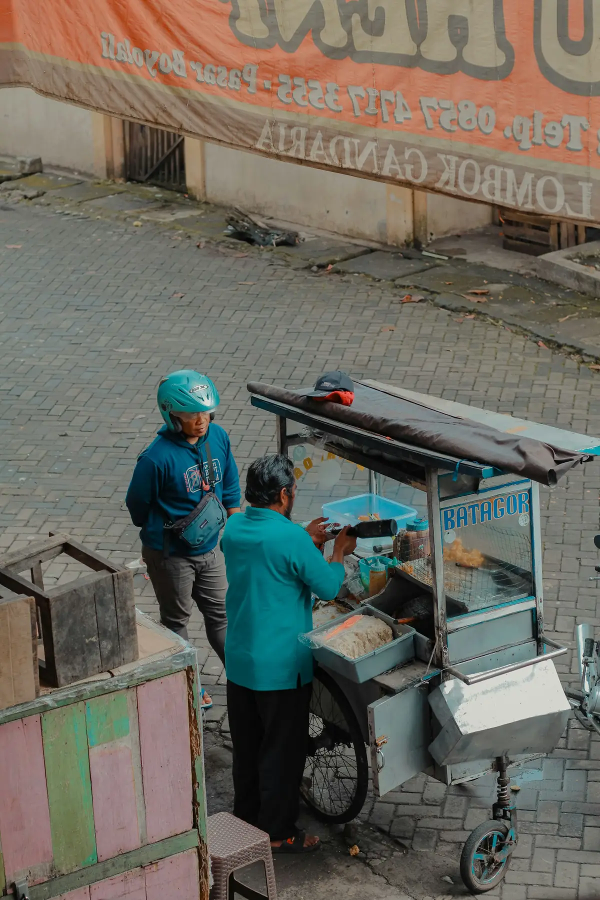 Pedagang melayani pembeli dari gerobak makanan di pinggir jalan