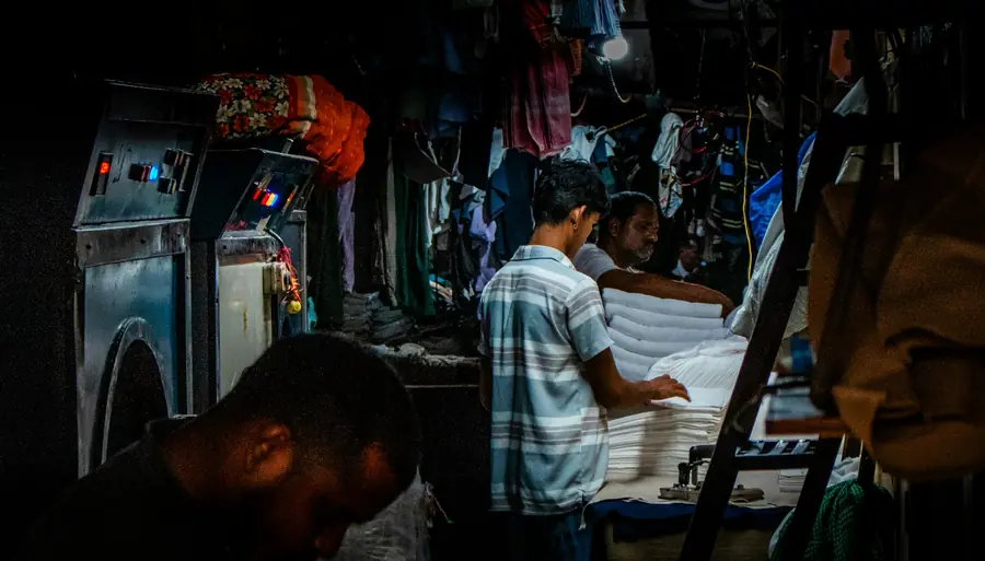 Pekerja laundry merapikan tumpukan pakaian putih